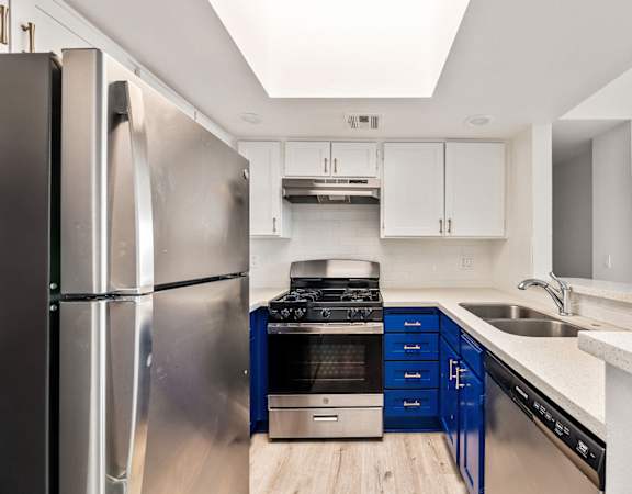 A modern kitchen with a stainless steel refrigerator and blue cabinets.