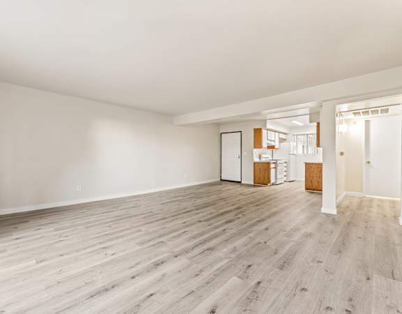 A spacious room with wooden flooring and white walls.