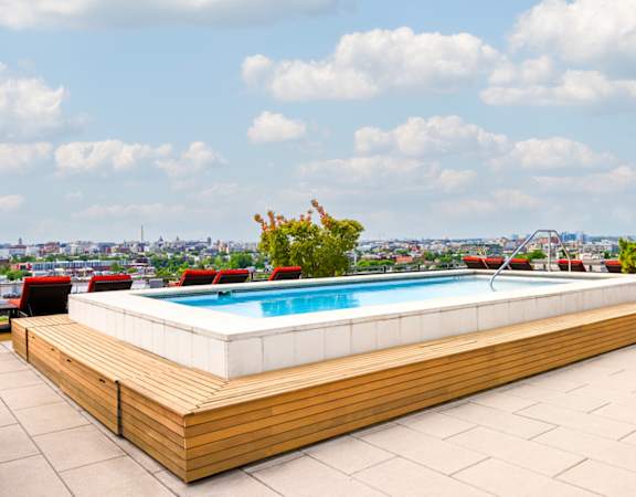 the pool on the rooftop of a building with a city in the background