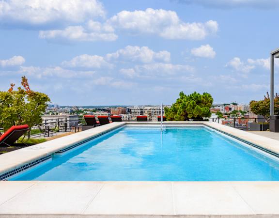 the pool on the roof of a building with a city in the background