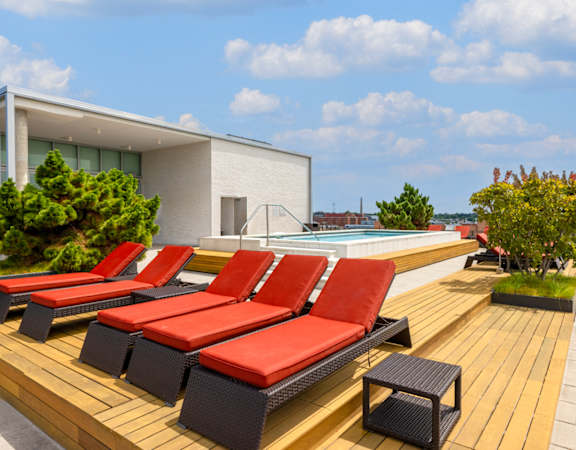 a row of red lounge chairs on a wooden deck next to a pool