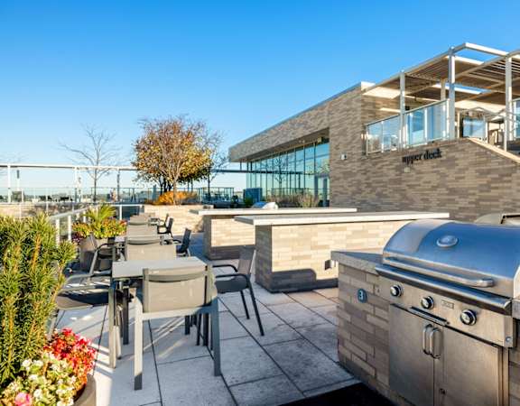 a patio with a barbecue grill and tables and chairs
