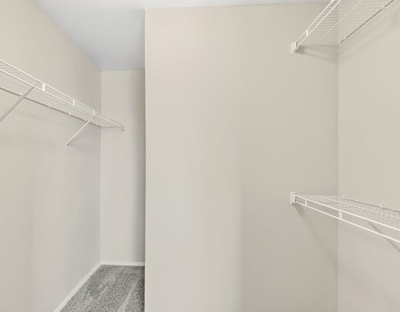 a spacious closet with two shelves and a hanging rack on the wall