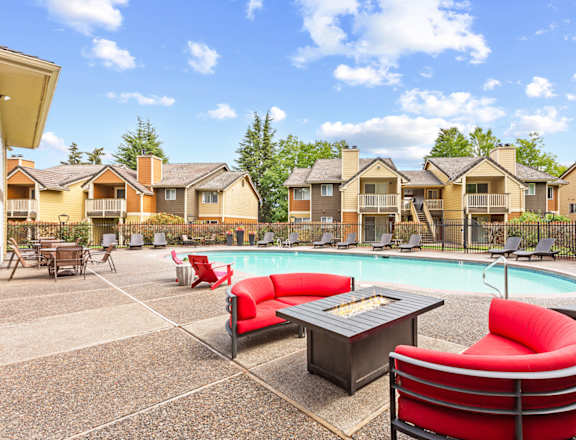 A pool area with red chairs and a hot tub in front of apartment buildings at MonteVista Apartments, Beaverton, OR