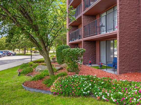 A red brick building with a balcony and a tree in front.