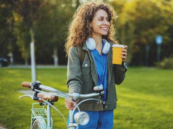 a woman standing next to a bike holding a cup of coffee