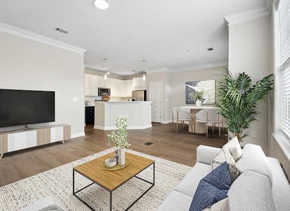 A living room with a white couch, a wooden coffee table, and a flat screen TV.