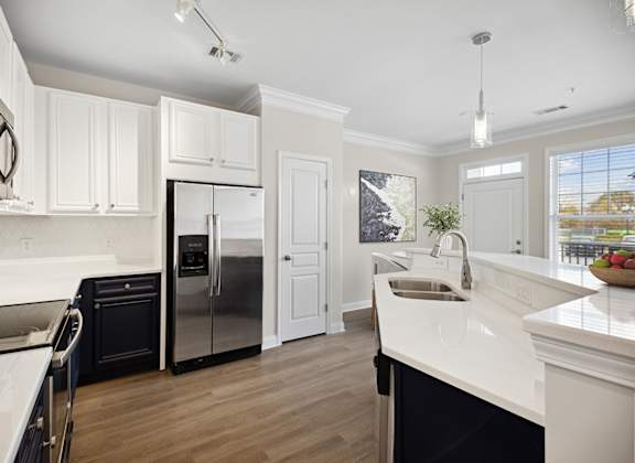 A modern kitchen with white cabinets and a black refrigerator.