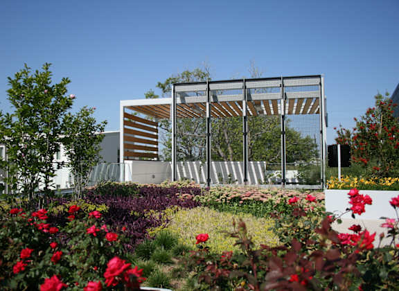 A modern building with a metal structure and a garden in front.