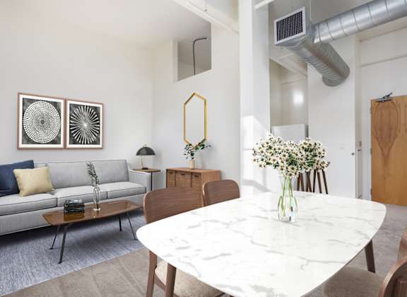 A modern living room with a grey sofa, a white marble table, and a grey carpet.