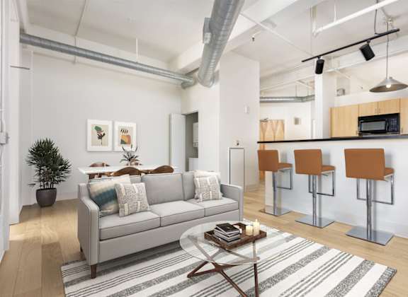 A living room with a grey couch, a coffee table, and a bar area with stools.