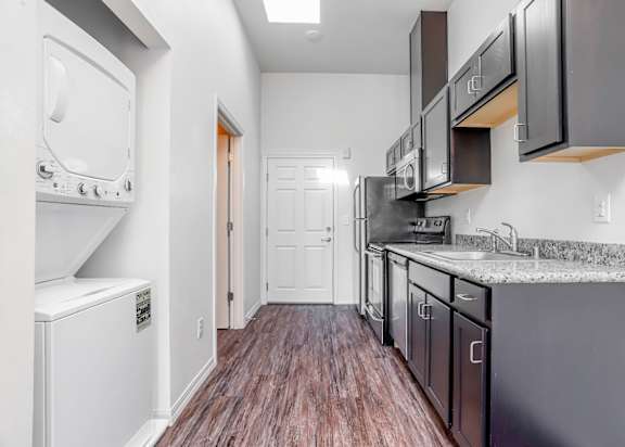 a kitchen with black cabinets and a white washer and dryer