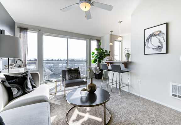 a living room with a large window and a ceiling fan