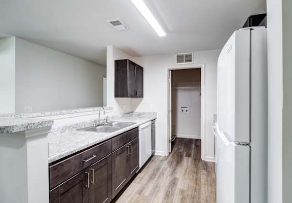A kitchen with a white fridge and brown cabinets.