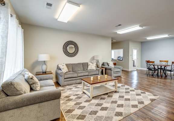 A living room with a couch, a coffee table, and a dining table.