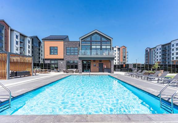 A large swimming pool in front of a building with a glass facade.