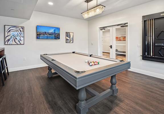 A pool table in a room with a television and picture frames on the wall.