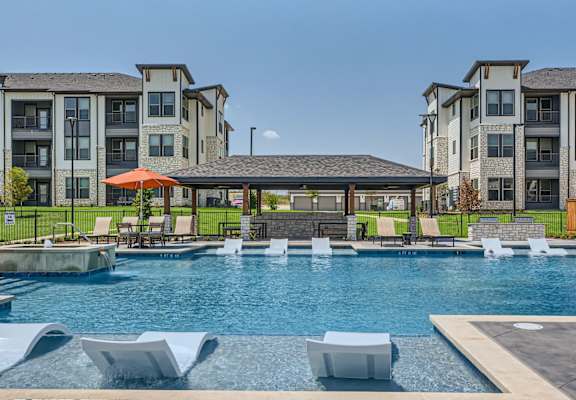 A swimming pool with a pavilion and chairs around it.