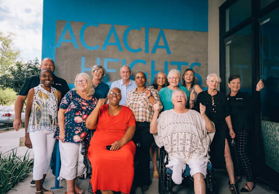 A group of people are standing in front of a blue wall with the words "ACACIA HEALTH" written on it.