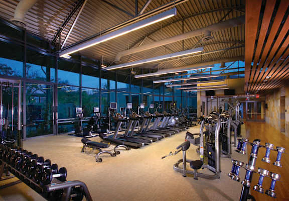 A gym with a variety of equipment including treadmills, weights, and exercise machines.