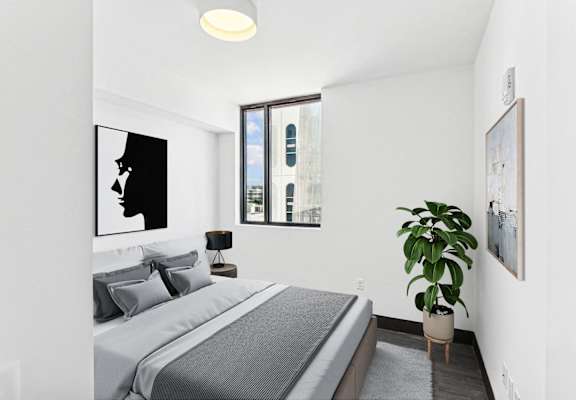 A bedroom with a bed, a potted plant, and pictures on the wall.