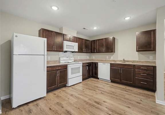 A kitchen with white appliances and wooden cabinets.