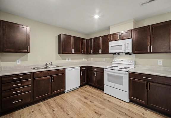 A kitchen with brown cabinets and white appliances.