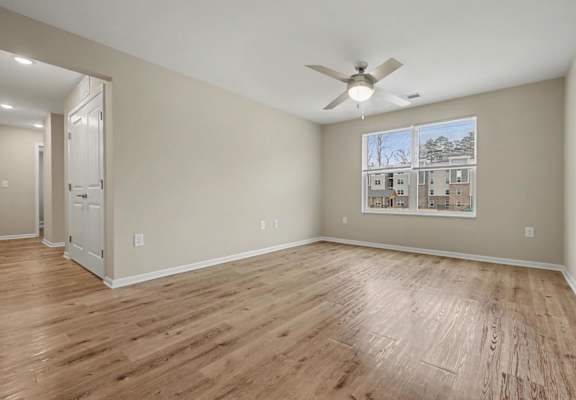 A room with a ceiling fan and a window showing a view of a building.