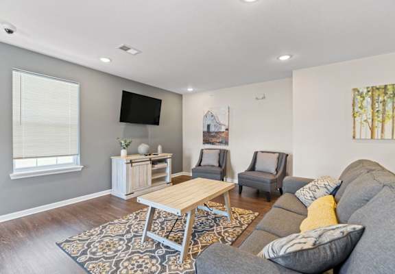 a living room with a couch and two chairs in front of a tv