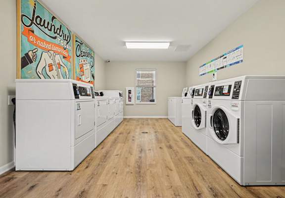 Laundry room with washers and dryers and a mural on the wall.