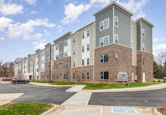 A large apartment complex with a parking lot in front.