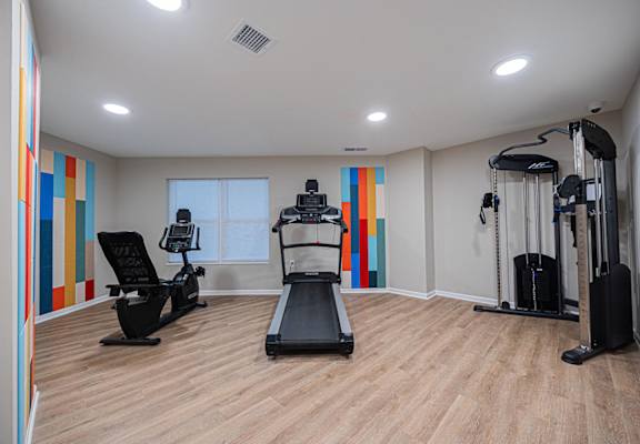 A gym with a treadmill, elliptical trainer, and a stationary bike.