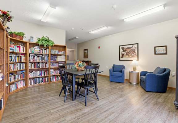 A room with a table, chairs, and a bookshelf filled with books.