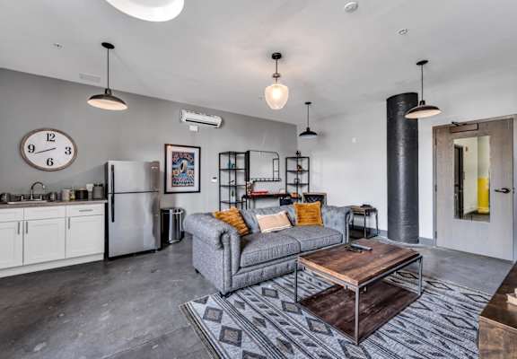 a living area with a couch coffee table and a refrigerator