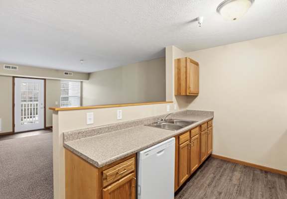 A kitchen with a white dishwasher and wooden cabinets.
