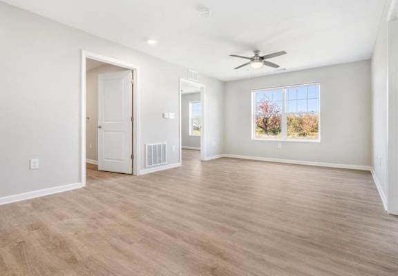 an empty living room with a ceiling fan and a window