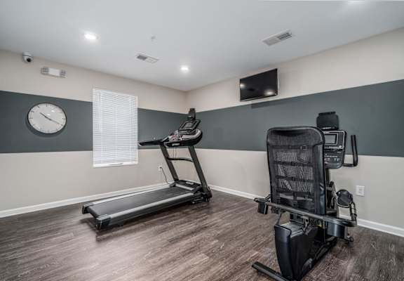 a gym with a treadmill and a clock on the wall