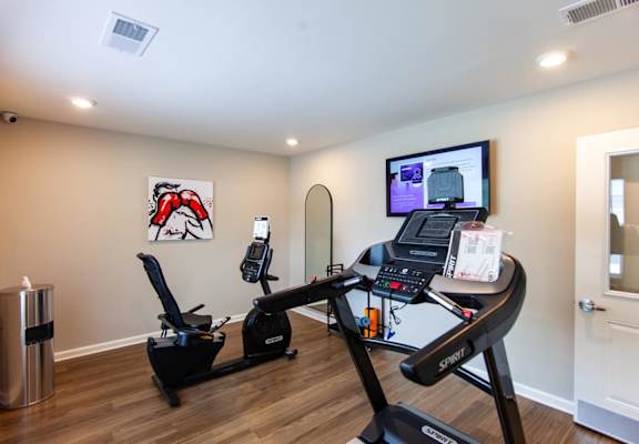 a home gym with a treadmill and a tv on the wall