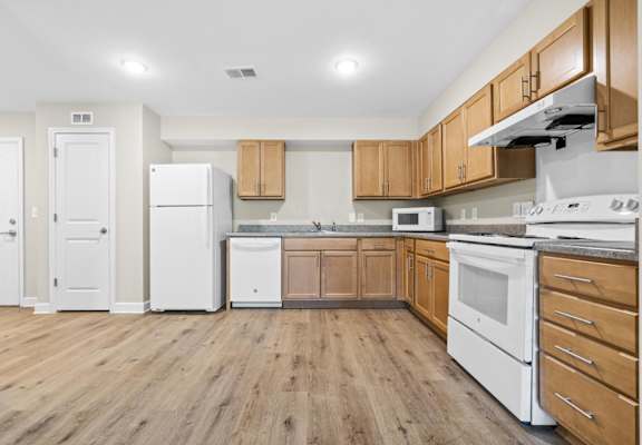 A kitchen with white appliances and wooden cabinets.