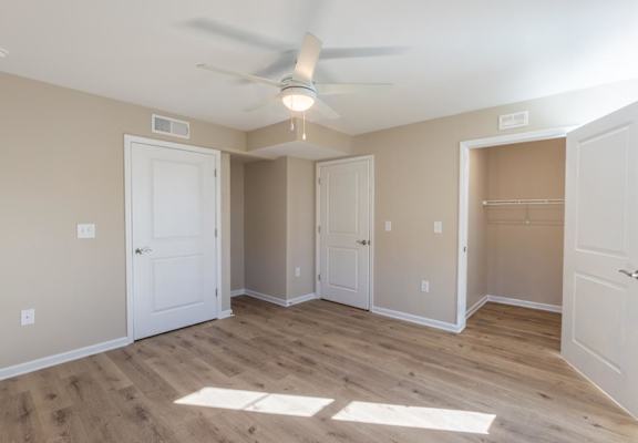 A room with a ceiling fan and wooden flooring.