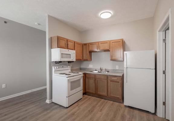A kitchen with white appliances and wooden cabinets.