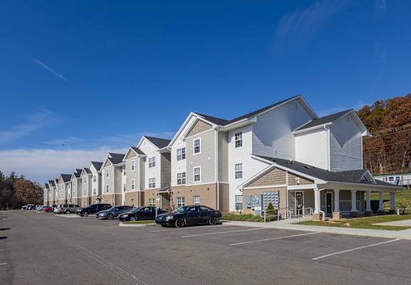 A row of townhouses with a parking lot in front.