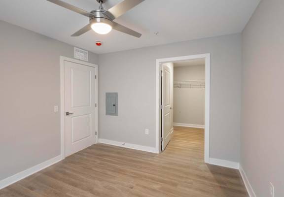 A room with a ceiling fan and a doorway leading to another room.