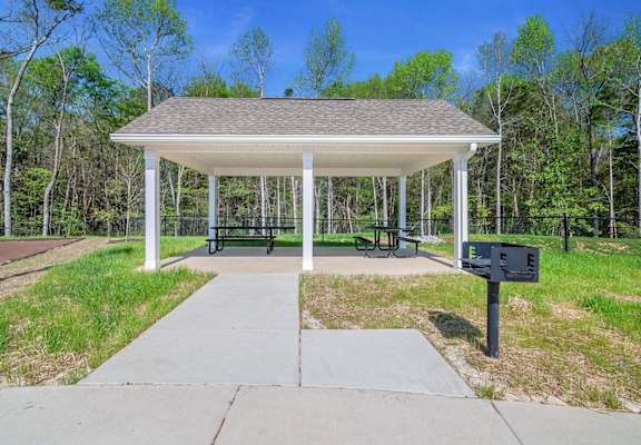 A pavilion with a white roof and a black mailbox is surrounded by trees.