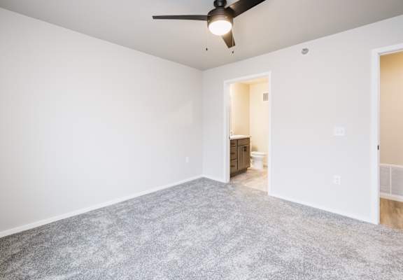 A room with a ceiling fan and carpeted floor.