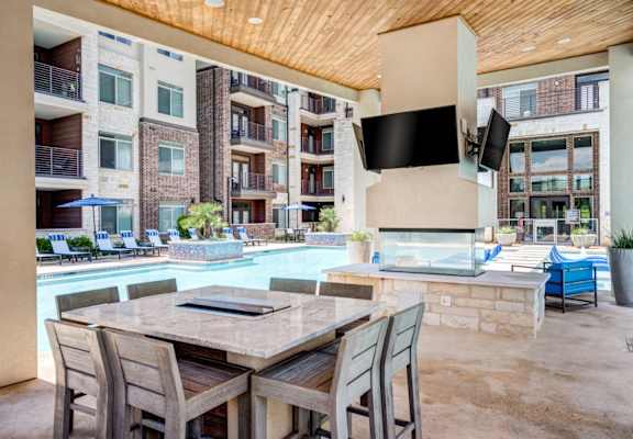 a patio with a table and chairs and a pool in front of a building at AMARA, San Antonio, 78257