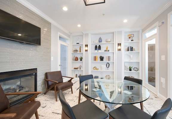 A modern living room with a glass table and chairs. at Vivant Woodholme, Pikesville
