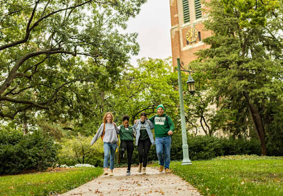 three people walking down a sidewalk near a playground