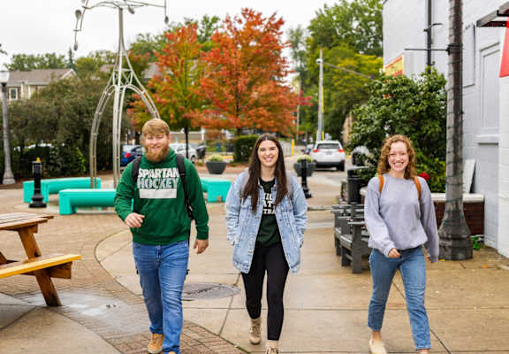 three people walking down a sidewalk near a playground