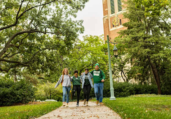 a group of people walking down a sidewalk on a college campus